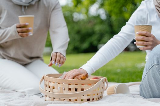 Deux personnes assises sur une couverture de pique-nique, partageant des aliments et des boissons dans un parc verdoyant.